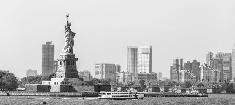 Statue of Liberty with Liberty State Park and Jersey City skyscrapers in background, USA. Black and white image.