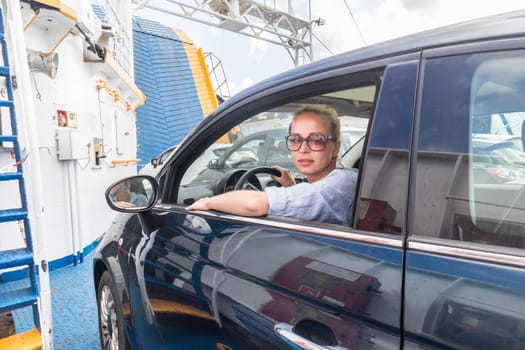 Female driver parking her car on ferry boat on trip to their summer vacations island destination. Sardinia, Italy. Water transport concept.