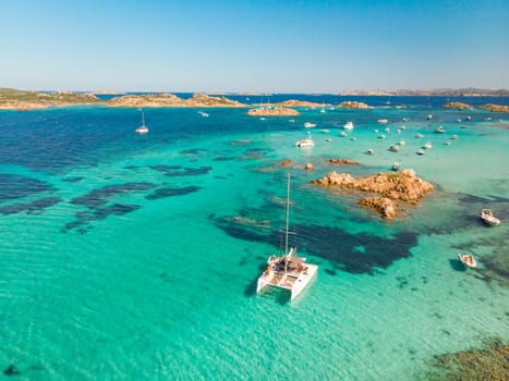 Drone aerial view of catamaran sailing boat in Maddalena Archipelago, Sardinia, Italy. Maddalena Archipelago is composed of Razzoli, Santa Maria and Budelli islands.