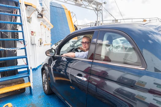 Female driver parking her car on ferry boat on trip to their summer vacations island destination. Sardinia, Italy. Water transport concept.