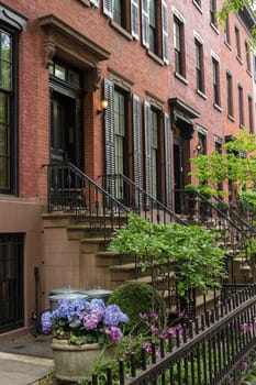 Row of old brownstone buildings along an empty sidewalk block in the Greenwich Village neighborhood of Manhattan, New York City, NYC, USA.