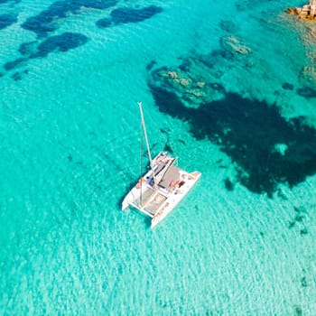 Drone aerial view of catamaran sailing boat in Maddalena Archipelago, Sardinia, Italy. Maddalena Archipelago is a group of islands between Corsica and north-eastern Sardinia.