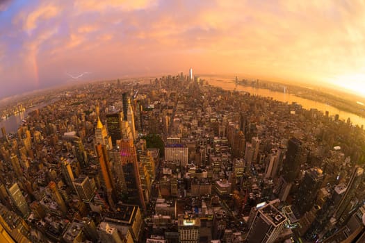 New York City skyline with Manhattan skyscrapers at dramatic vibrant after the storm sunset, USA. Rainbow and lightnings can be seen in background over Brooklyn bridge.