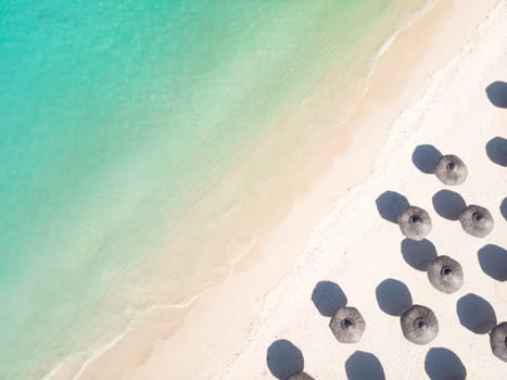 Aerial view of amazing tropical white sandy beach with palm leaves umbrellas and turquoise sea, Mauritius.