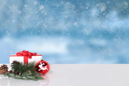 Christmas greeting card.  Christmas gift and Christmas decoration on white table over abstract winter landscape. Template for your product display montage.
