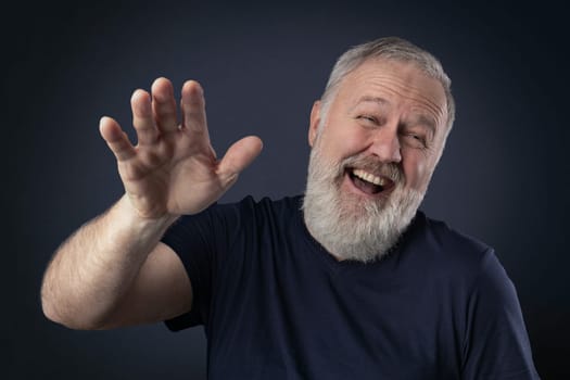 Elderly man with gray beard laughing with his palm up
