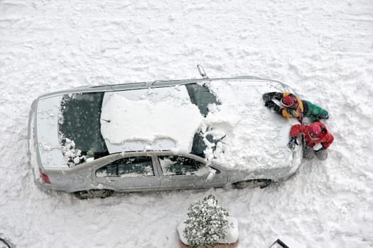 Elevated view of children play in snow covered parking lot