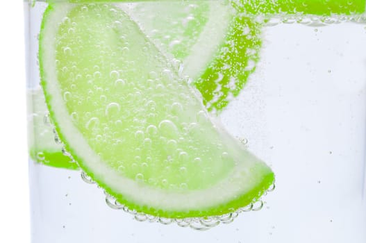 Pieces of fresh juicy lime sink into clear water.