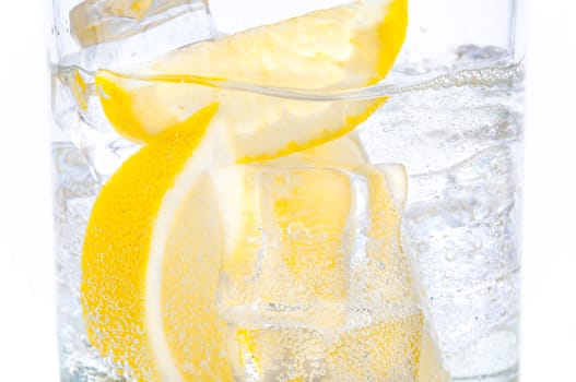 In a glass with cubes of melting ice slices of a juicy yellow lemon.