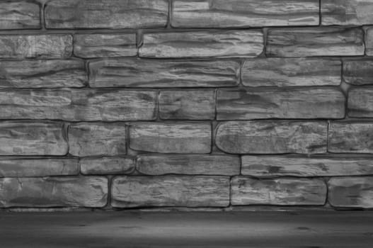 The wall is made of large bricks of black and white color and wooden boards with a spot of illumination.