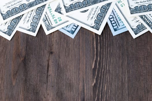 A frame of one hundred dollar bills at the top and a background of dark wood.