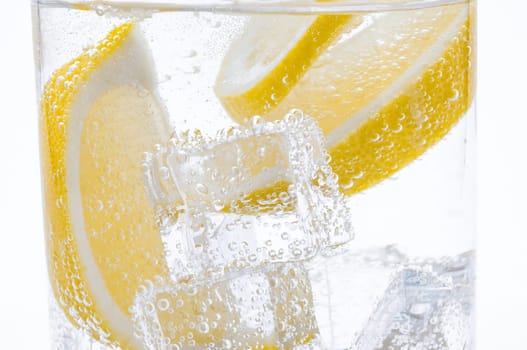 Slices of fresh juicy lemon drop into the cocktail with crystal clear water.