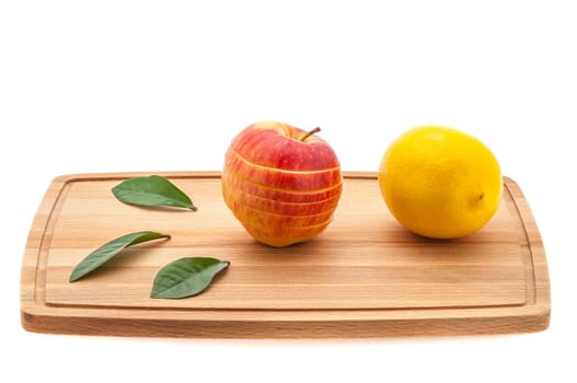 apple tasty, fresh and juicy with green leaves and lemon on a cutting board made of wood.