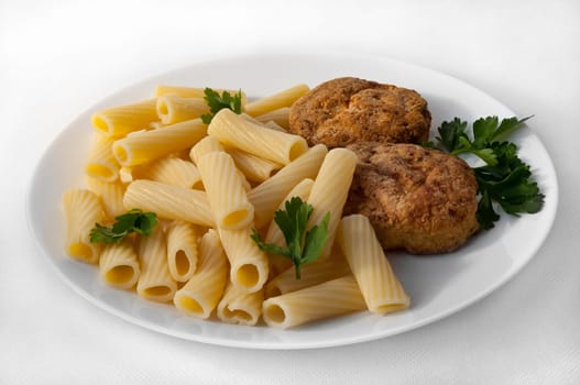 A large plate with pasta and two cutlets, decorated with parsley.