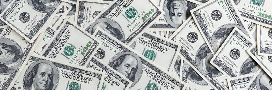 A pile of one hundred US banknotes with president portraits. Cash of hundred dollar bills, dollar background image.