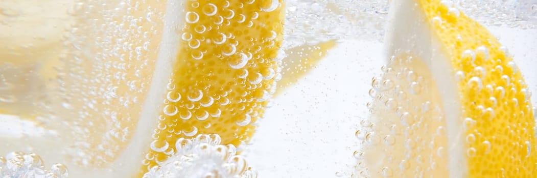 In a glass with cubes of melting ice slices of a juicy yellow lemon.