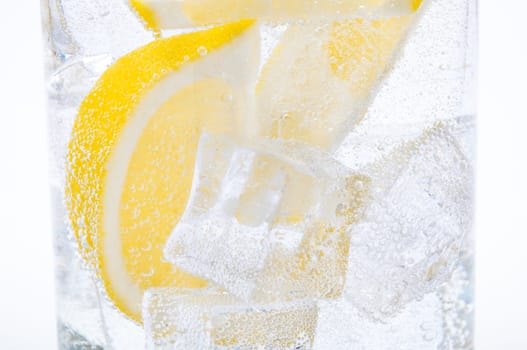 Ice, lemon slices and crystal clear water in a glass.