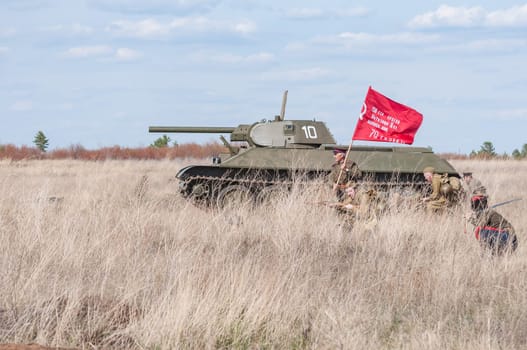 2018-04-30 The Samara, Russia. A commander with a banner leads into the battle of Soviet soldiers. Reconstruction of hostilities in April 1945.