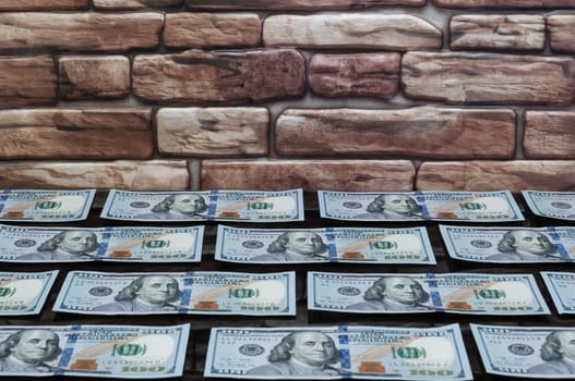 bills of one hundred dollars on a table of black glass near a brick wall