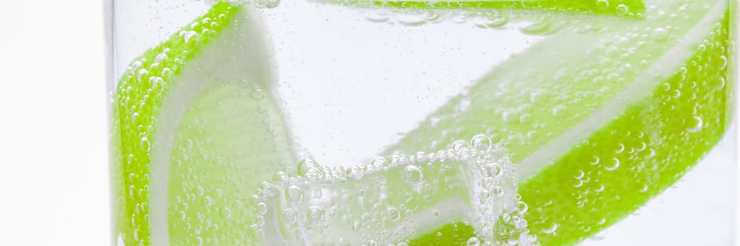 Slices of fresh juicy lemon drop into the cocktail with crystal clear water.