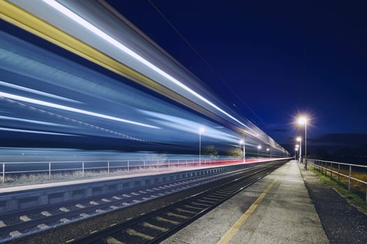 Light trails of passenger train commuting to railroad station at night.