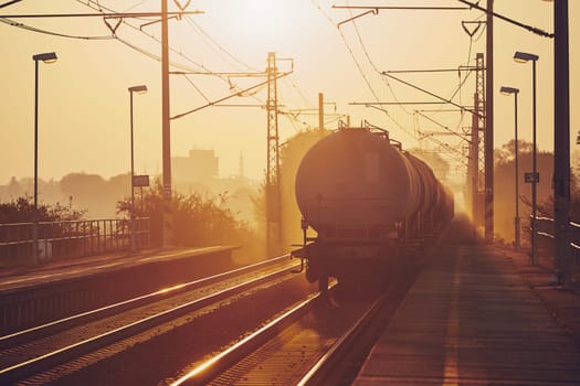 Freight train leaving from railroad station at sunrise.