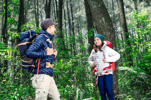 Young asian couple with backpack exploring the green forest