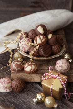 Little plate with truffles and chocolates in front of a dark wooden background