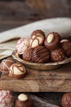 Little plate with truffles and chocolates in front of a dark wooden background