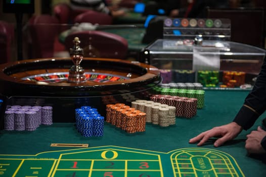 Casino, gambling and entertainment concept - roulette table and stack of poker chips