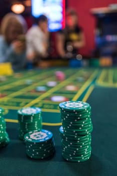 Casino, gambling and entertainment concept - stack of poker chips on a green table
