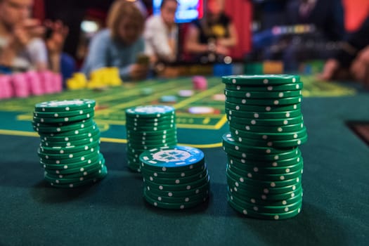 Casino, gambling and entertainment concept - stack of poker chips on a green table