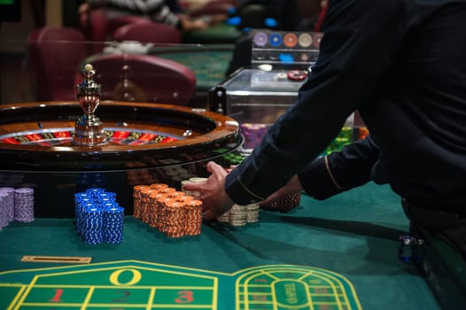 Casino, gambling and entertainment concept - roulette table and stack of poker chips
