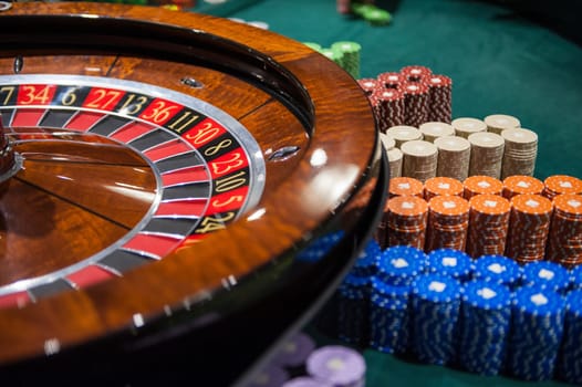 Casino, gambling and entertainment concept - roulette table and stack of poker chips