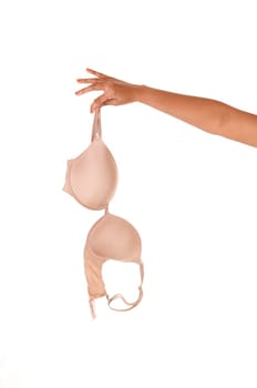 A close up image of the arm of a woman holding a beige bra, isolated.for white background.