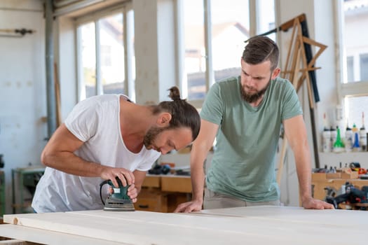 two men in workwear in a carpenter's workshop