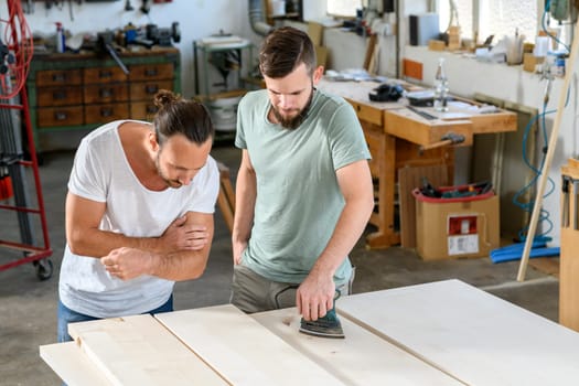 two men in workwear in a carpenter's workshop