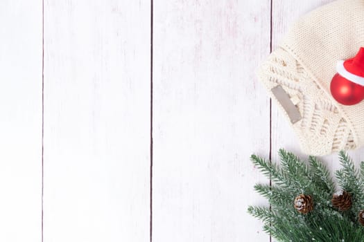 Christmas or winter decoration background. Compostion from christmas tree branches and a winter sweater on a wooden table. Space for design on left site. Top view.