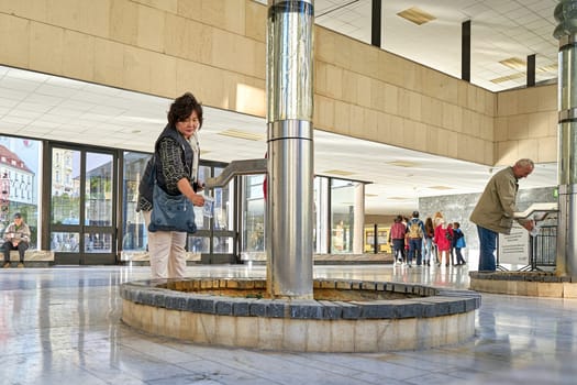 Tourists on a Fountain in the Thermal Spring Colonnade in the city center of Karlovy Vary in the Czech Republic