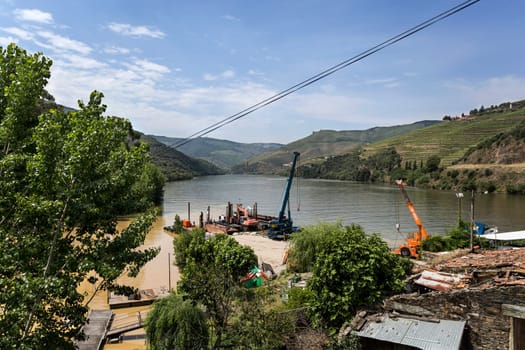 Large works at the confluence of the muddy waters of the Torto River (left) with the Douro in the famous Port Wine Region, Portugal