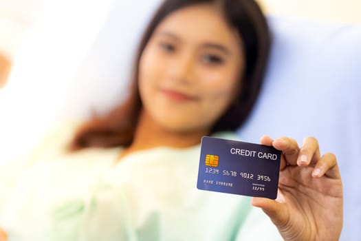 Portrait of Young adult female Patient with credit card in bed of hospital ward