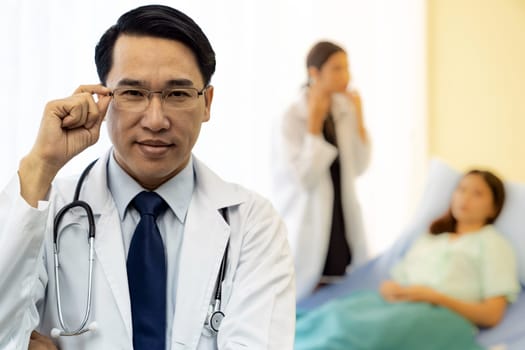 Portrait of Young adult Doctor with nurse and Patient in background.