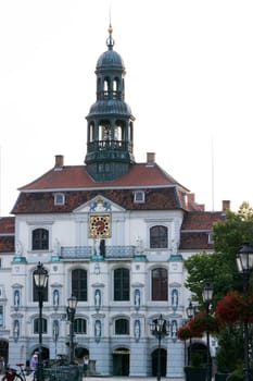 LÜNEBURG, NIEDERSACHSEN, GERMANY - JULI 27, 2018:.Vintage Straßenlaterne Laterne mit Blumenbeet. Historisches Rathaus im Hintergrund in Lueneburg Deutschland...Lueneburg, Lower Saxony, Germany - July 27, 2018:.Vintage street lamp lantern with flowerbed. Historic city hall in the background in Lueneburg Germany.