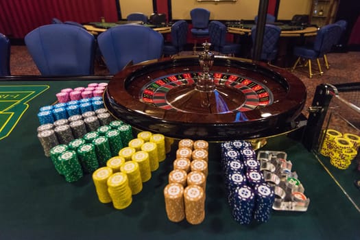 Casino, gambling and entertainment concept - roulette table and stack of poker chips