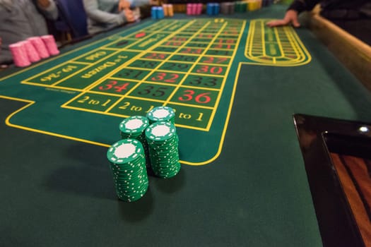 Casino, gambling and entertainment concept - stack of poker chips on a green table