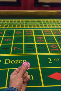 Casino, gambling and entertainment concept - male hand with stack of poker chips on a green table background