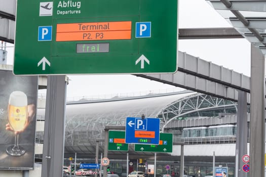 DUESSELDORF, NRW, GERMANY - FEBRUARY 20, 2017: Access road to the departure terminal of the airport Duesseldorf. Signposts and suspension railway and cars in the background.
