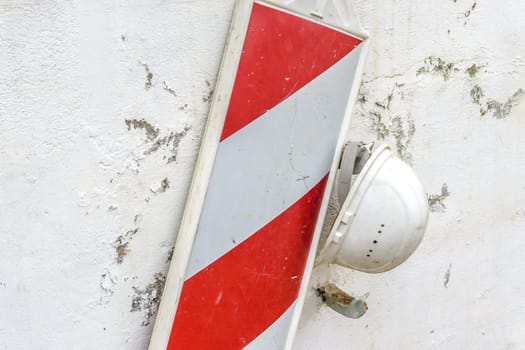 Old protection helmet and traffic sign hanging on weathered wall