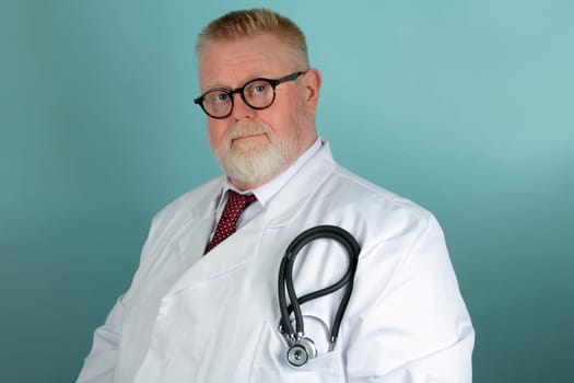 Matured, confident caucasian male medical doctor with stetescope and in white coat, on blue background