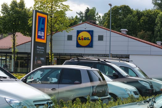 Mülheim Ruhr, Nrw, Germany - June 04, 201k7:Aldi and Lidl supermarket parking lot in Muelheim in Mülheim, Ruhr area, view over the street. A car drives to a parking lot. Outside the supermarket are people.